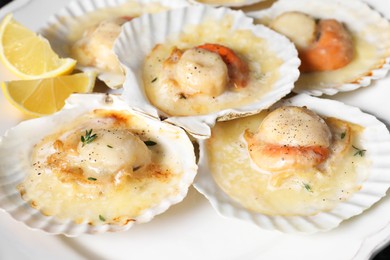 Photo of Fried scallops in shells and lemon on plate, closeup