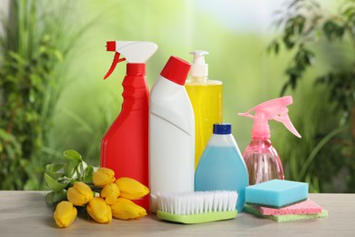 Spring cleaning. Detergents, supplies and beautiful flowers on wooden table outdoors