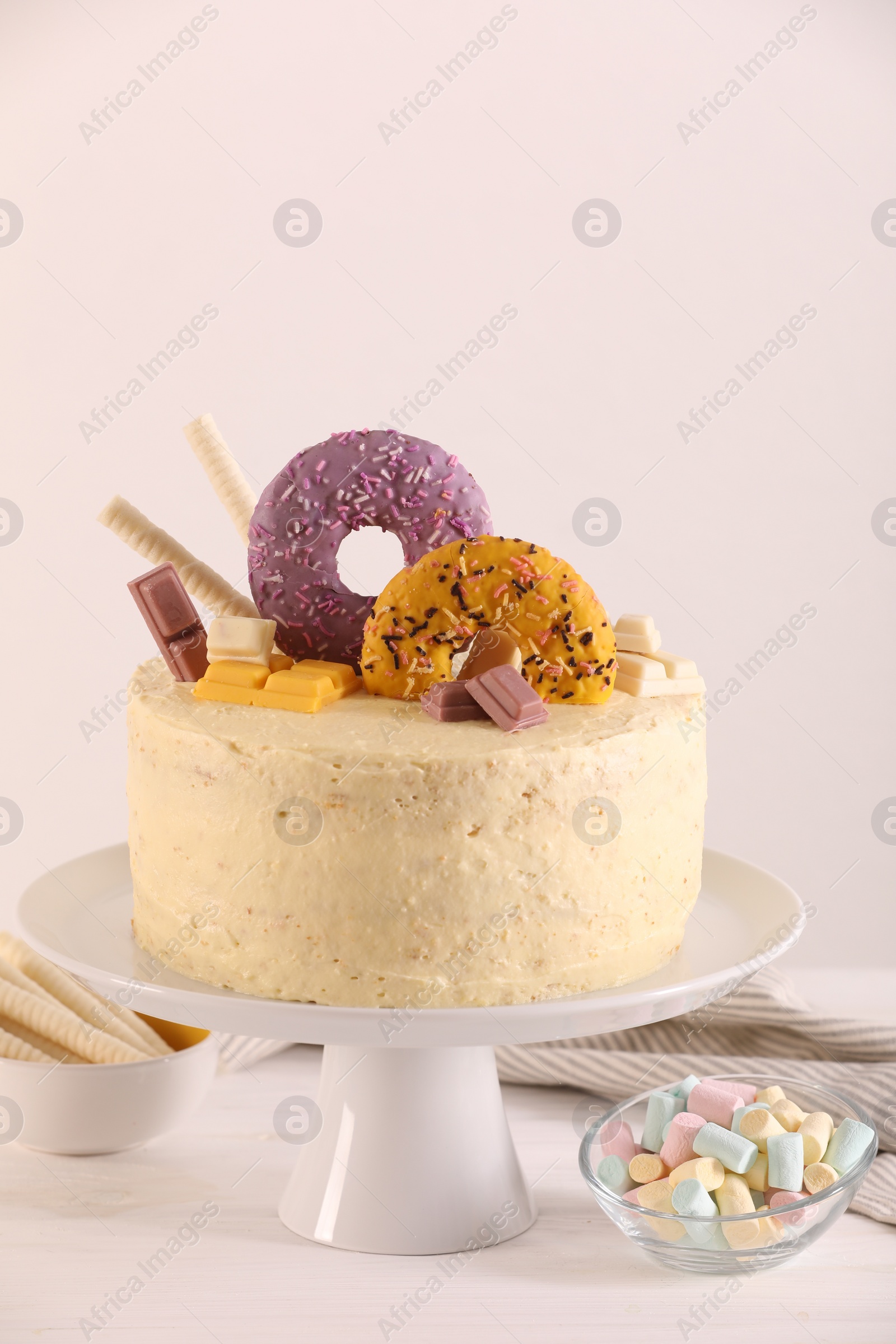 Photo of Delicious cake decorated with sweets and marshmallows on white wooden table