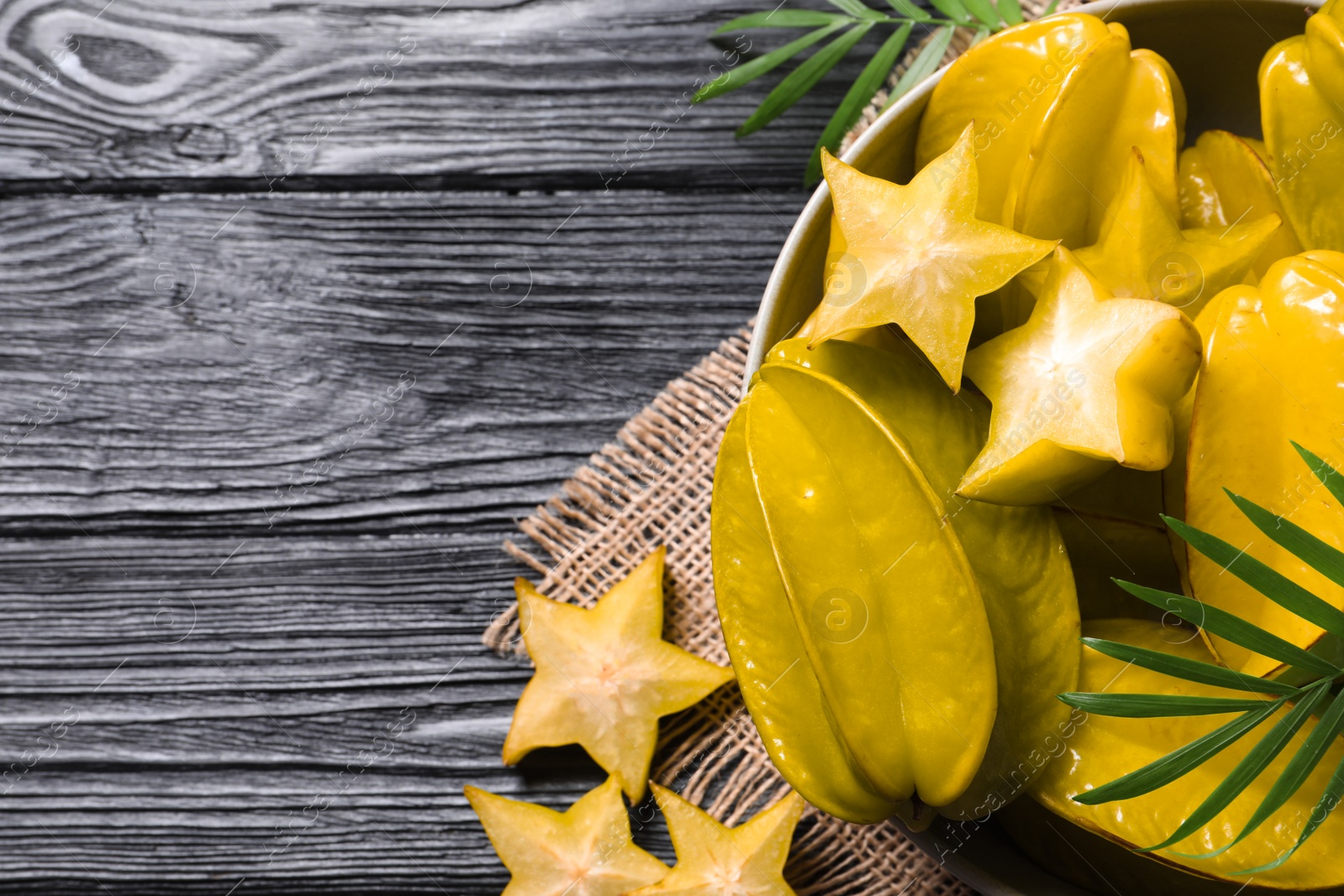 Photo of Delicious carambola fruits on black wooden table, flat lay. Space for text