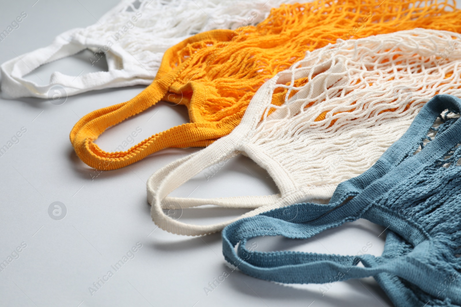 Photo of Different string bags on light grey background, closeup