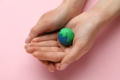Photo of Woman holding model of planet on pink background, closeup. Earth Day
