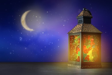 Beautiful decorative Arabic lantern on table at night, space for text. Fanous as Ramadan symbol
