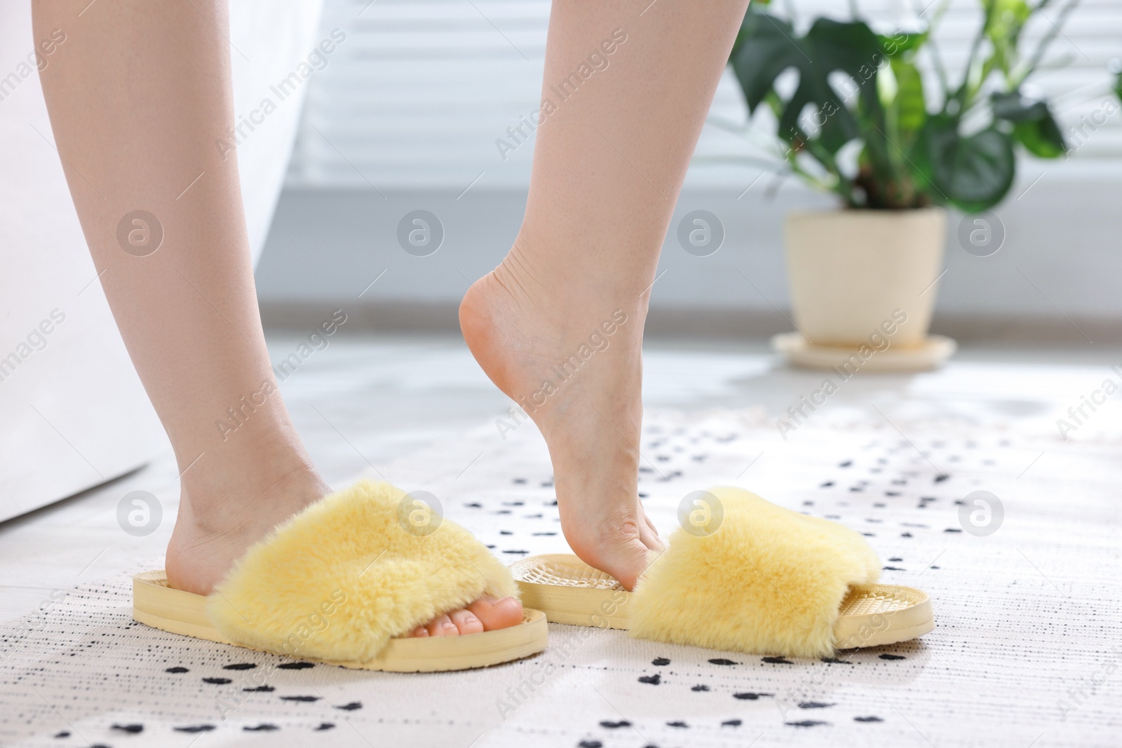 Photo of Woman in yellow soft slippers at home, closeup