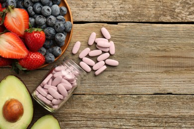 Photo of Vitamin pills in bottle and fresh fruits on wooden table, flat lay. Space for text