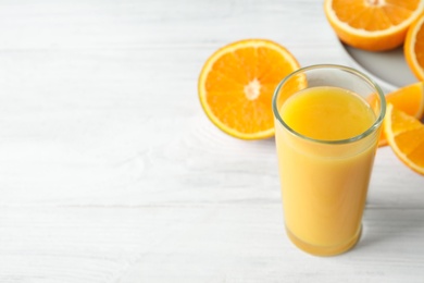 Photo of Glass of orange juice and fresh fruits on white wooden table. Space for text