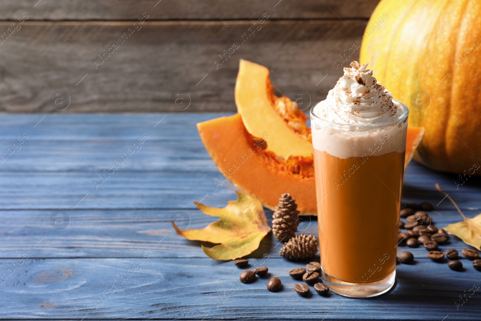 Photo of Glass with tasty pumpkin spice latte on wooden table. Space for text