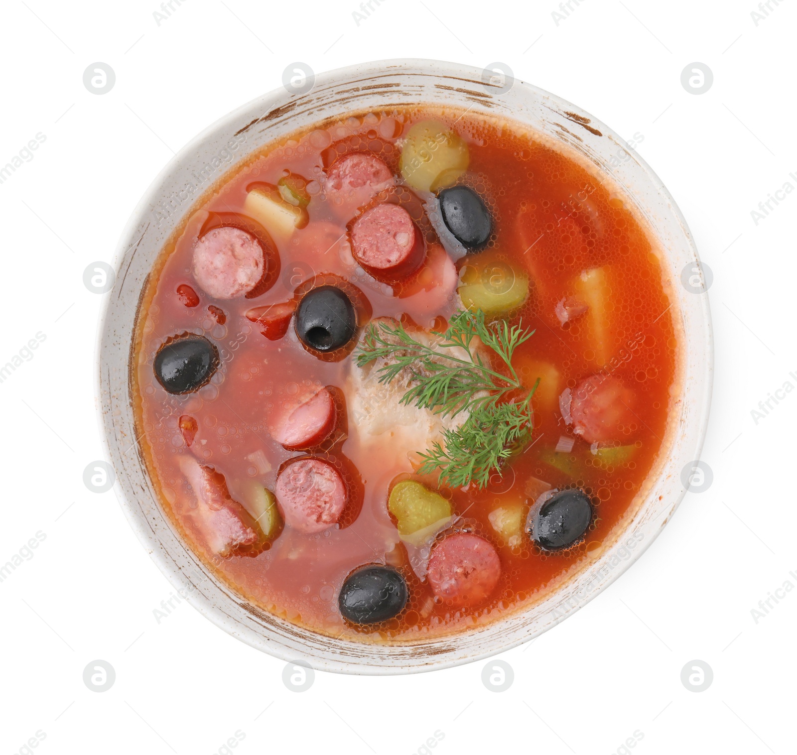 Photo of Meat solyanka soup with thin dry smoked sausages in bowl isolated on white, top view