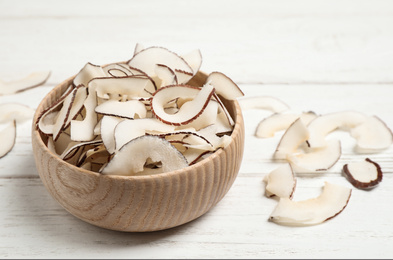 Photo of Tasty coconut chips on white wooden table
