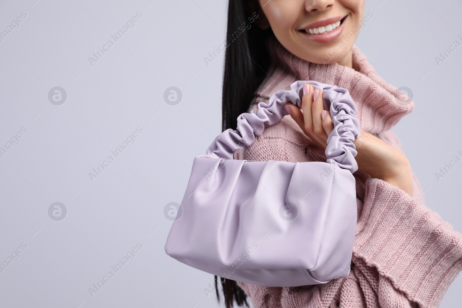 Photo of Fashionable young woman with stylish bag on light background, closeup. Space for text