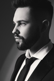 Handsome bearded man in stylish suit on grey background. Black and white effect