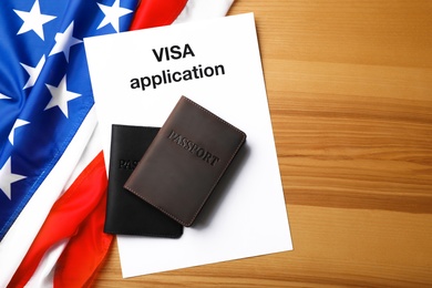 Flat lay composition with flag of USA, passports and visa application on wooden background