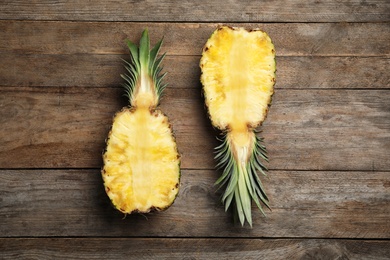 Photo of Halves of fresh pineapple on wooden background, top view