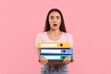 Shocked woman with folders on pink background