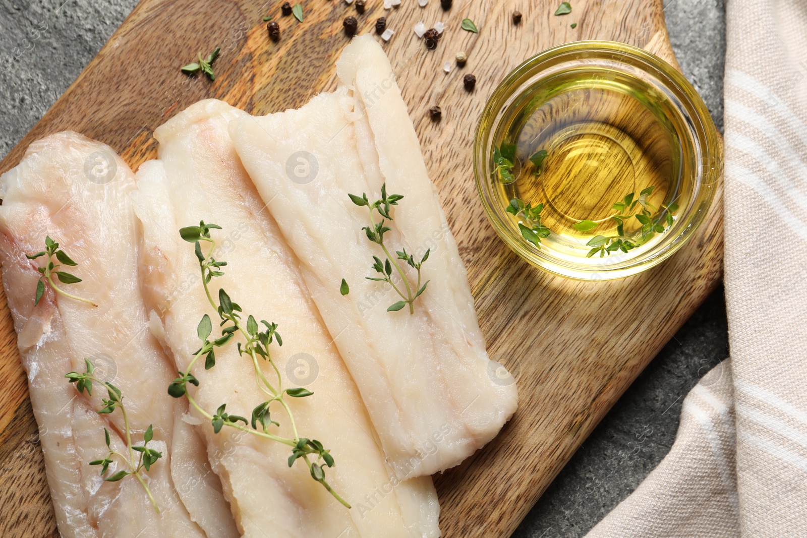 Photo of Raw cod fish, microgreens, oil and spices on grey textured table, top view