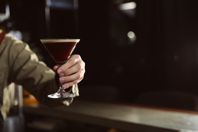 Photo of Barman holding espresso martini cocktail in pub, closeup. Space for text