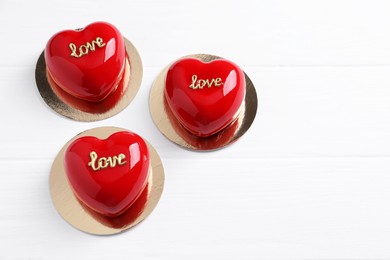 Photo of St. Valentine's Day. Delicious heart shaped cakes on white wooden table, above view. Space for text