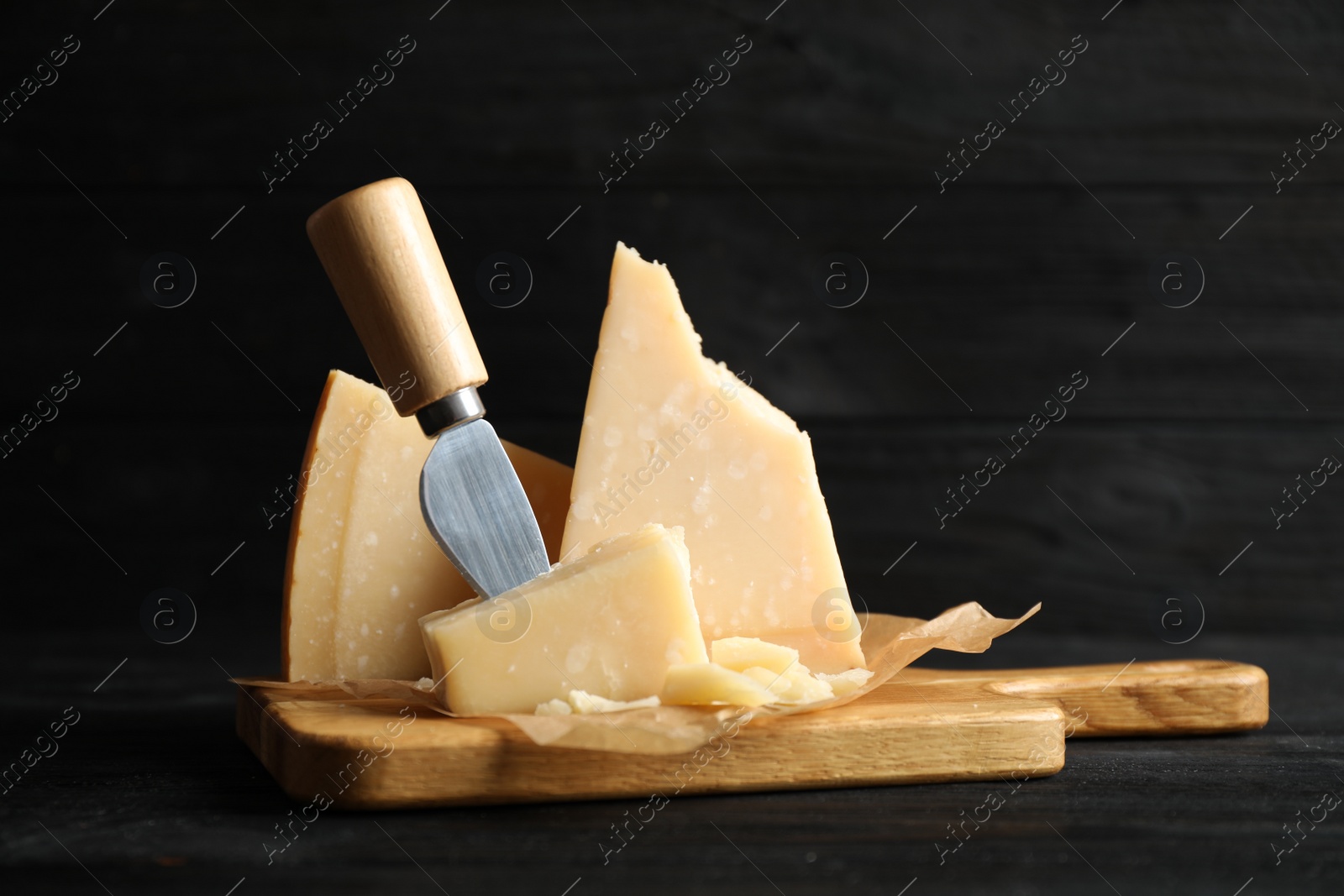 Photo of Pieces of Parmesan cheese and knife on black wooden table