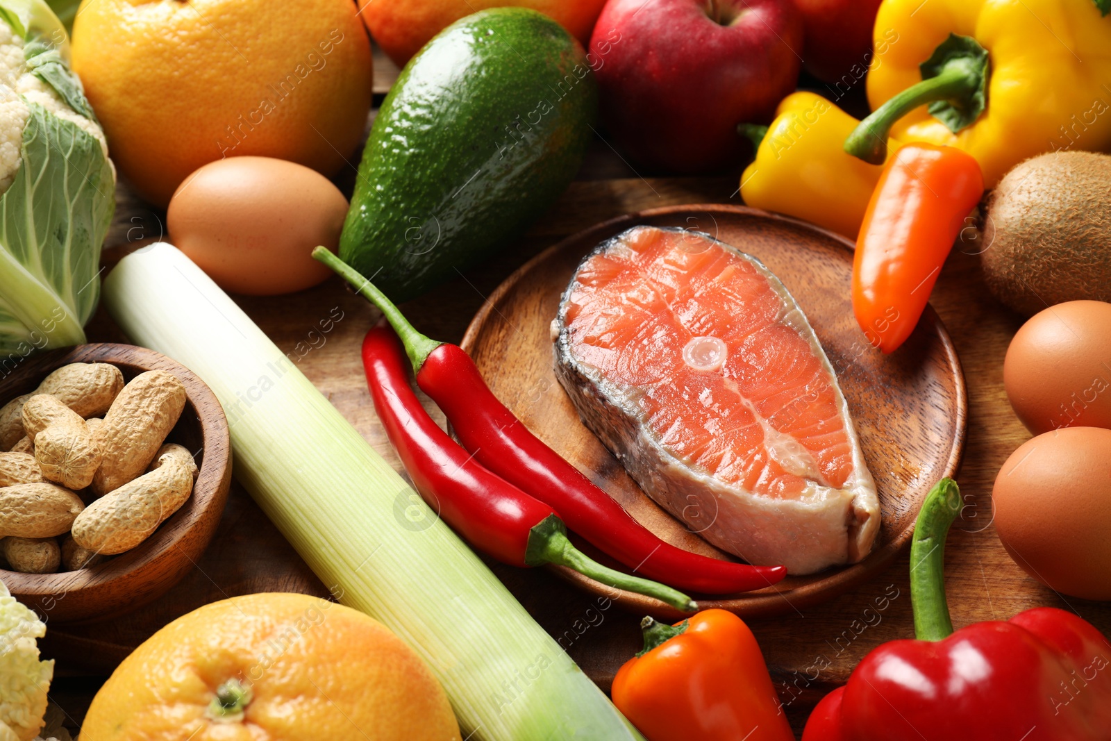 Photo of Healthy meal. Different vegetables and raw salmon on wooden table, closeup