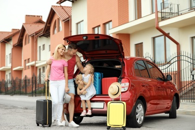 Photo of Happy family near car trunk with suitcases outdoors