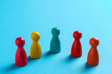 Colorful pawns on light blue background, closeup. Social inclusion concept