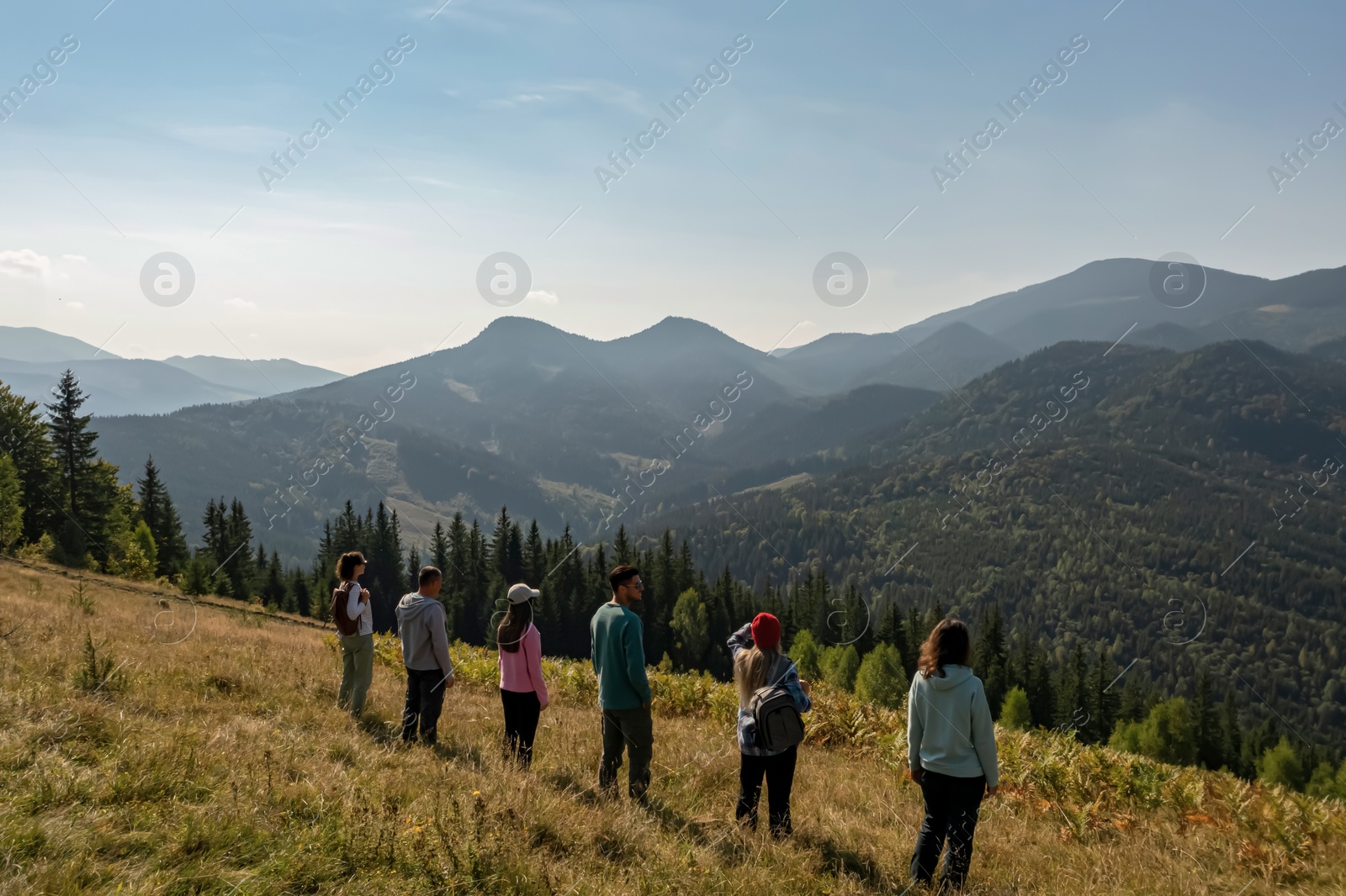 Image of Group of tourists on hill in mountains, back view