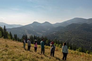 Image of Group of tourists on hill in mountains, back view