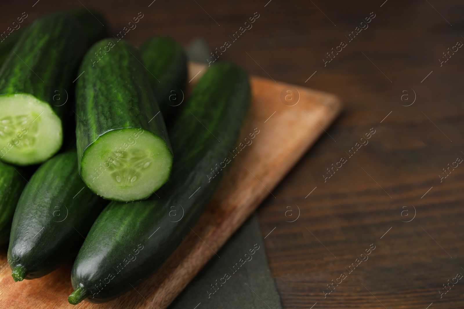 Photo of Fresh cucumbers on wooden table, closeup. Space for text