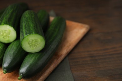 Photo of Fresh cucumbers on wooden table, closeup. Space for text