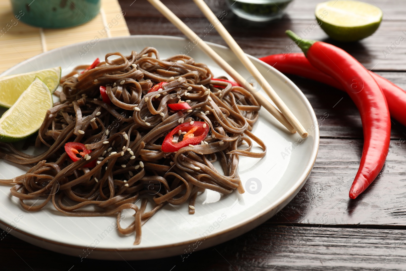 Photo of Tasty buckwheat noodles (soba) with chili pepper served on wooden table, closeup