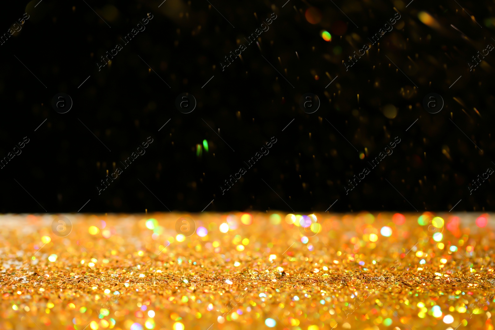 Photo of Many golden paillettes against black background. Space for text