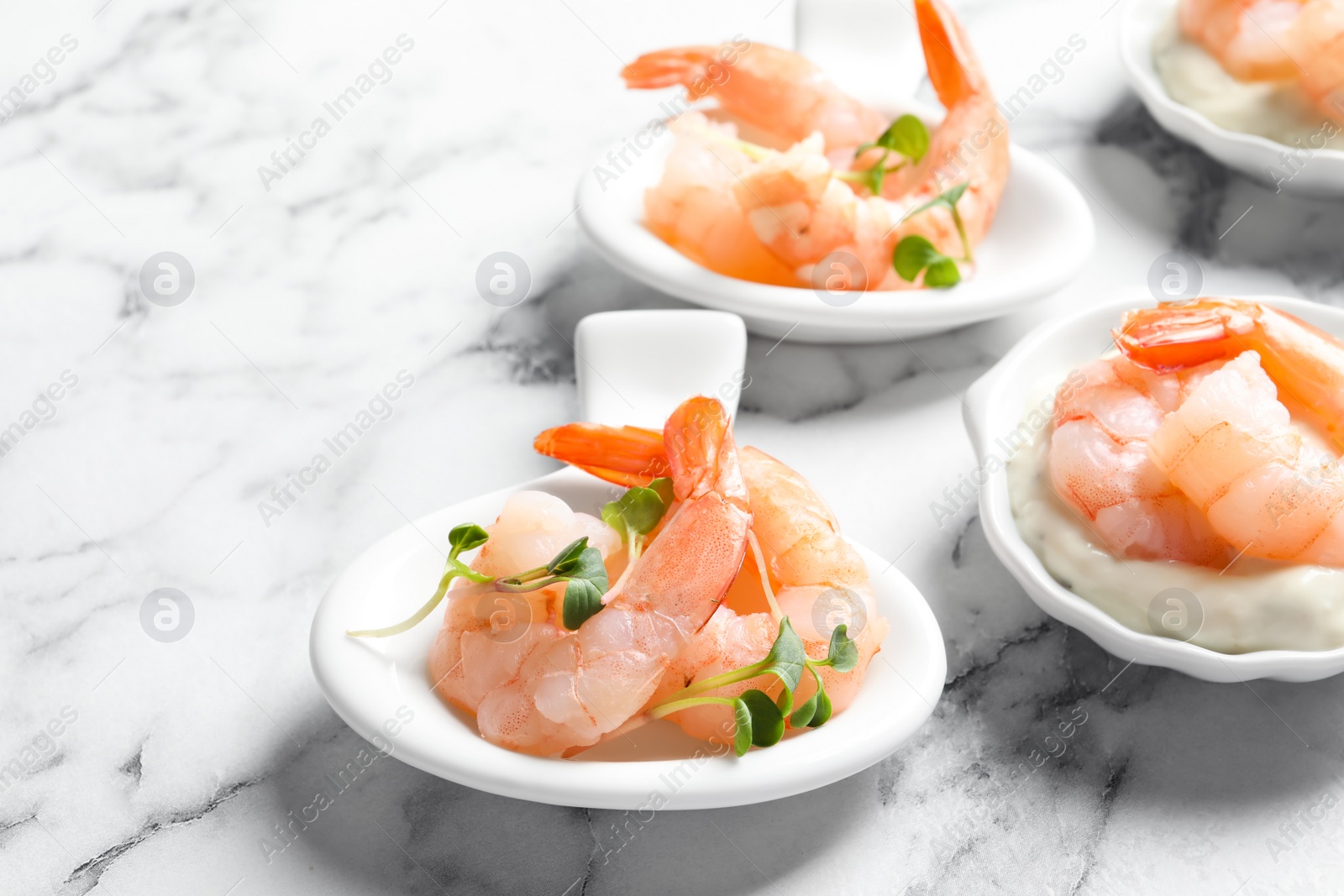 Photo of Bowls with boiled shrimps and sauce on light background