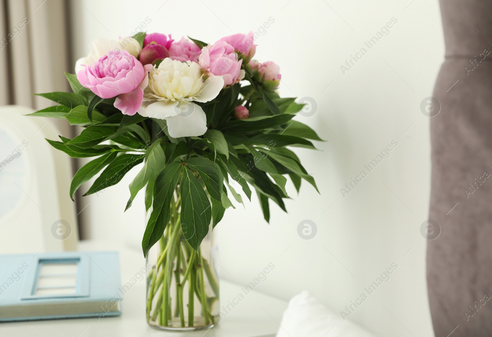 Photo of Vase with bouquet of beautiful peonies on table in room, space for text