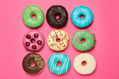 Different delicious glazed doughnuts on pink background, flat lay
