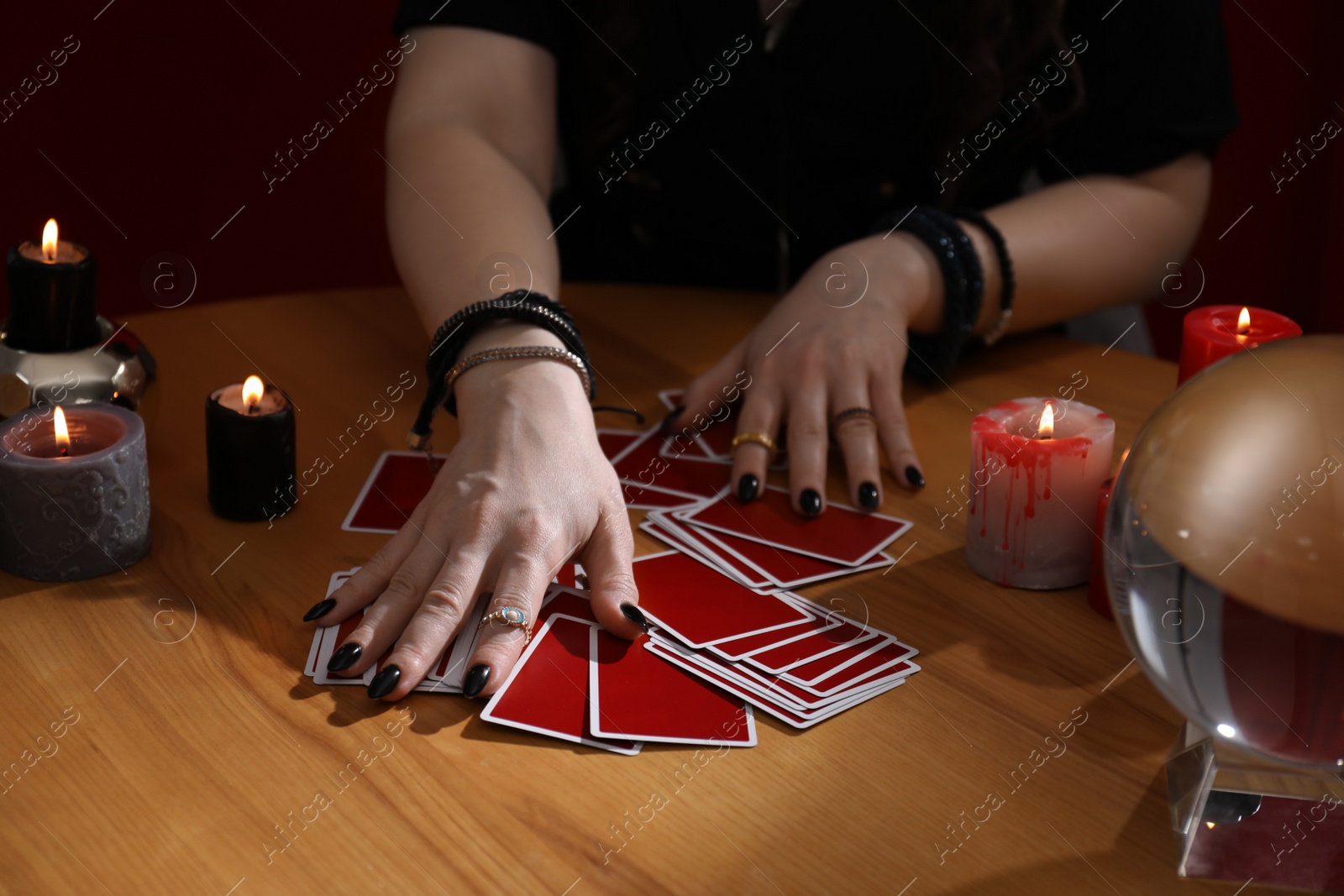 Photo of Soothsayer predicting future with cards at table indoors, closeup