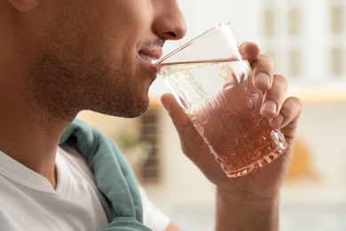 Photo of Man drinking pure water from glass in kitchen, closeup