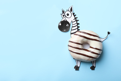 Photo of Funny zebra made with donut on light blue background, top view. Space for text