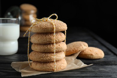 Photo of Delicious sugar cookies and glass of milk on black wooden table, closeup