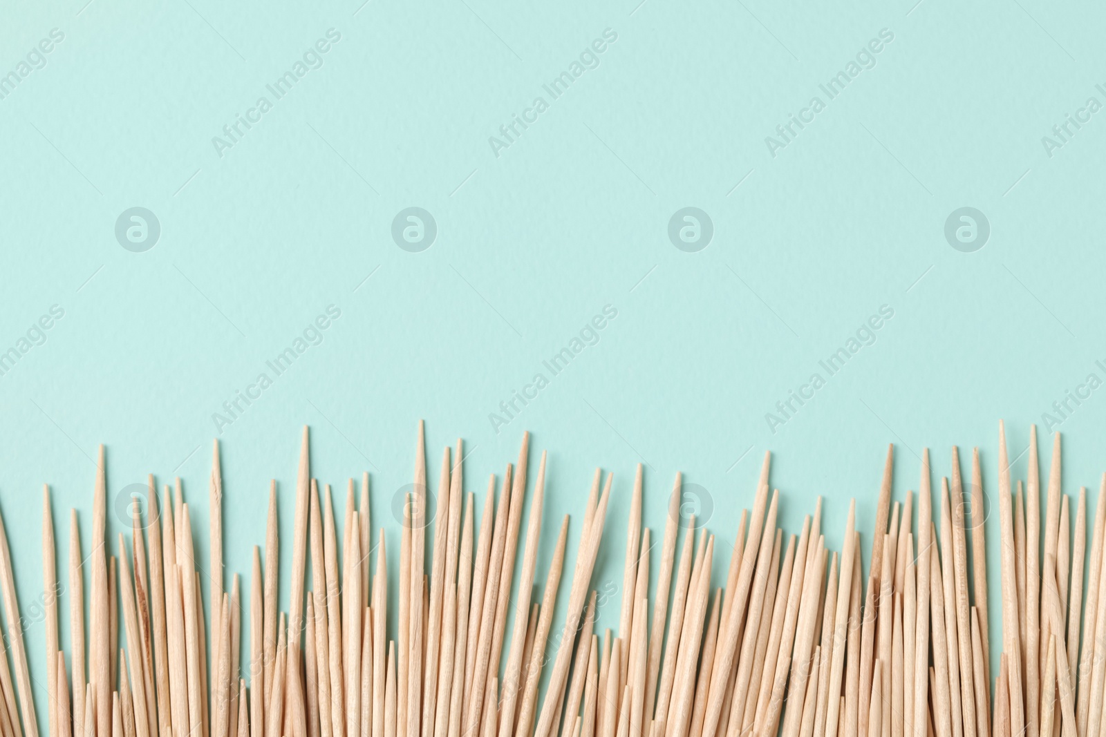 Photo of Wooden toothpicks on light blue background, flat lay. Space for text