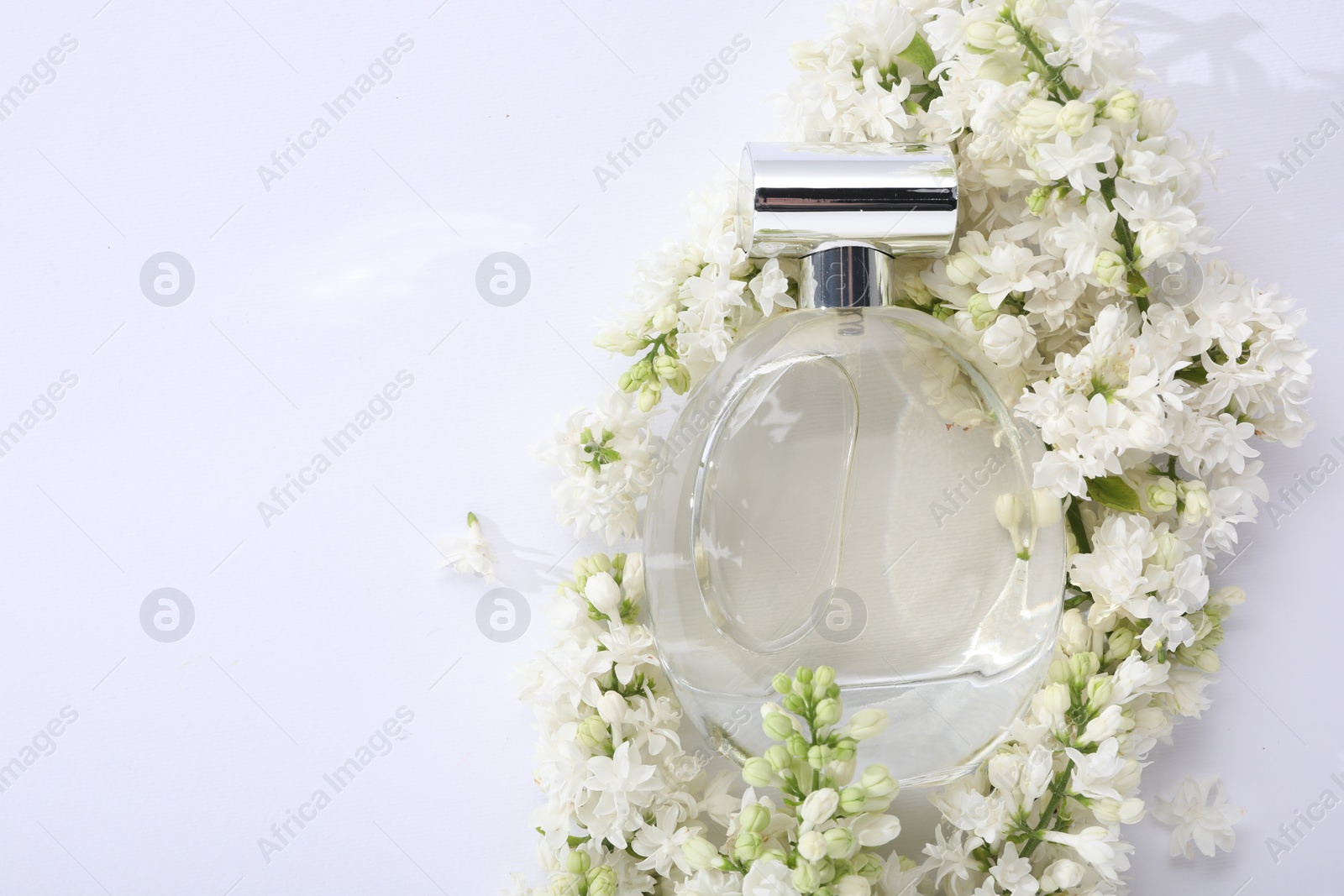 Photo of Luxury perfume and floral decor on white background, top view. Space for text