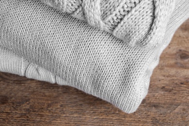 Image of Stack of folded warm sweaters on wooden table, closeup