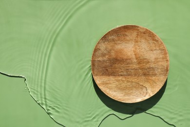 Photo of Presentation of product. Wooden podium in water on green background, top view. Space for text