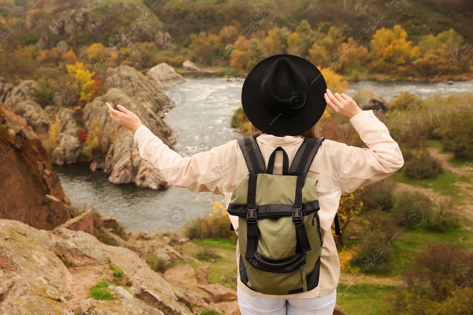 Photo of Traveler with backpack enjoying beautiful view near mountain river. Autumn vacation