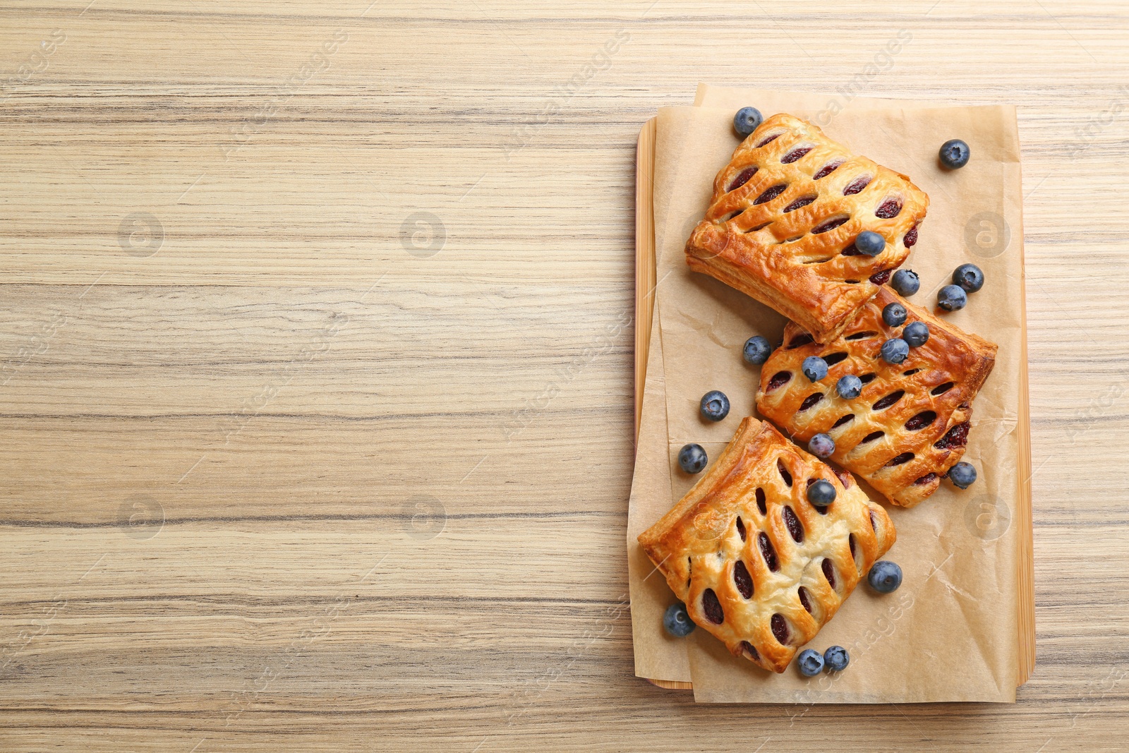 Photo of Fresh delicious puff pastry with fresh berries served on wooden table, top view. Space for text