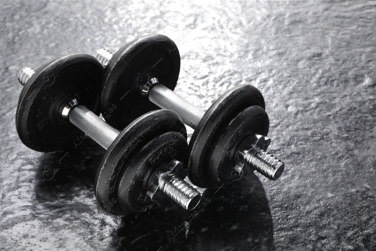 Photo of Two barbells on dark textured floor, closeup