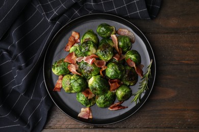 Photo of Delicious roasted Brussels sprouts and bacon on wooden table, top view