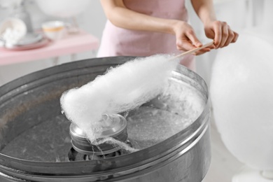 Photo of Woman making cotton candy using modern machine indoors, closeup