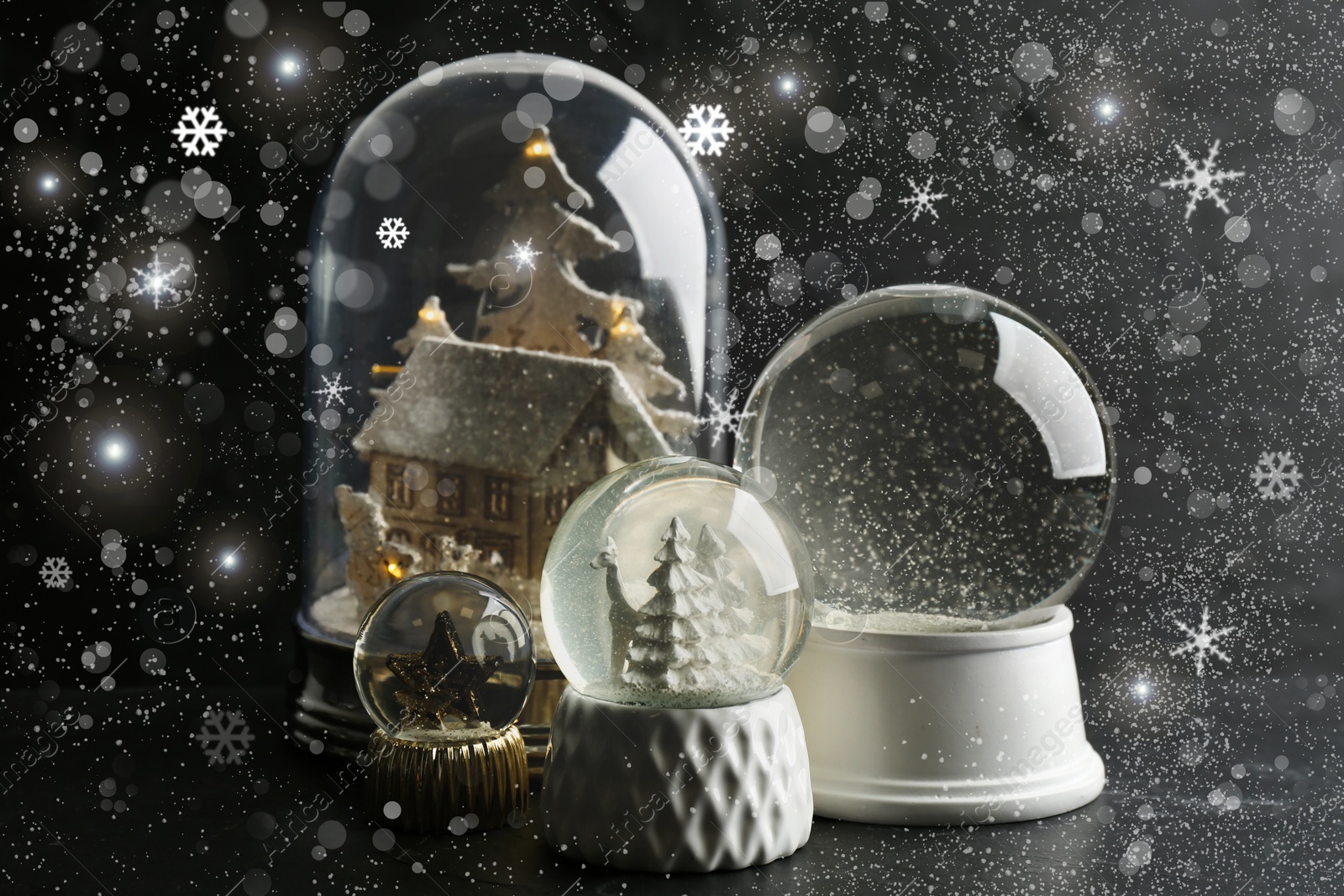 Image of Beautiful Christmas snow globes on dark grey background with snowflakes and bokeh effect