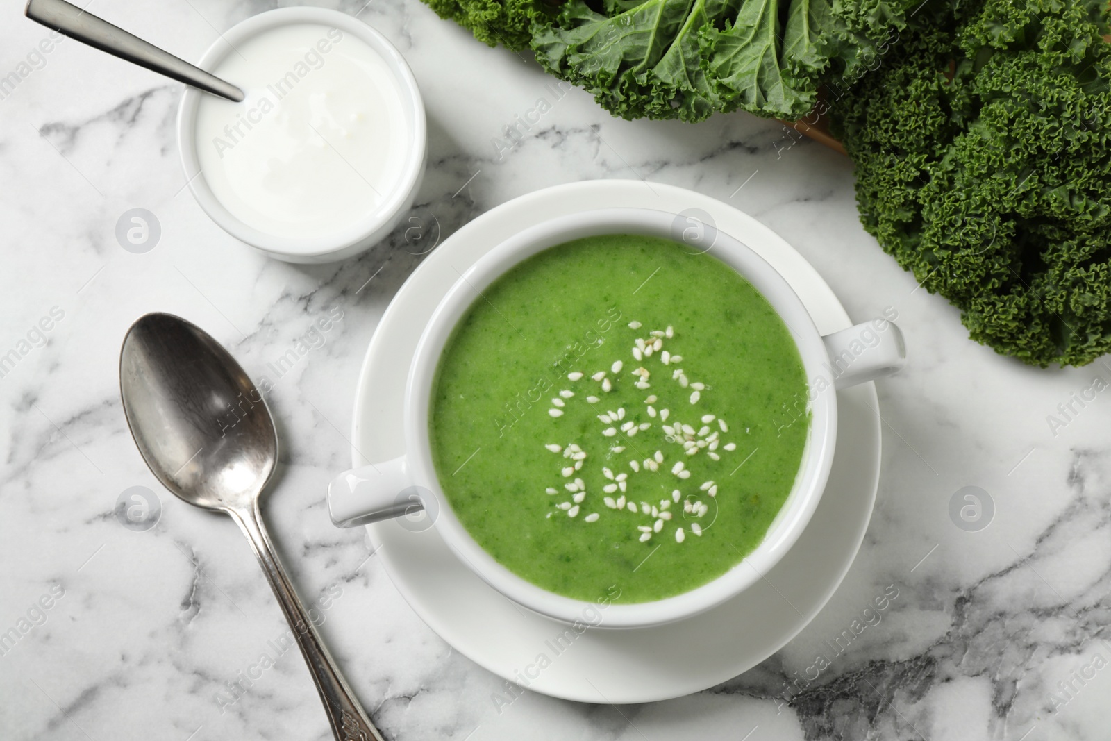 Photo of Tasty kale soup served on white marble table, flat lay