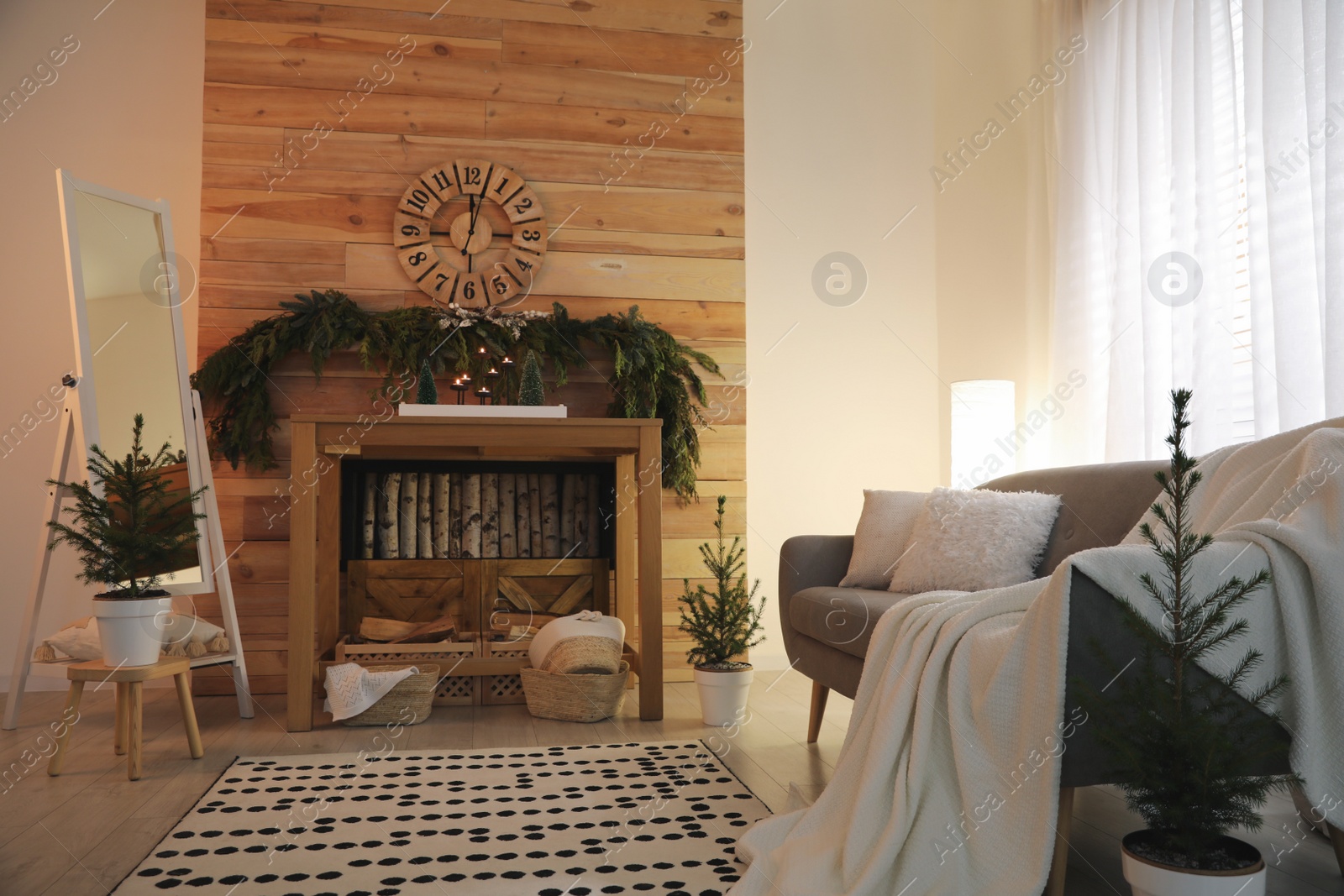 Photo of Cozy room interior with console table and conifer garland near wooden wall
